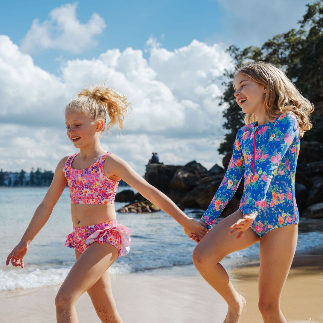 girls skipping along beaching wearing ocean tales swimwear