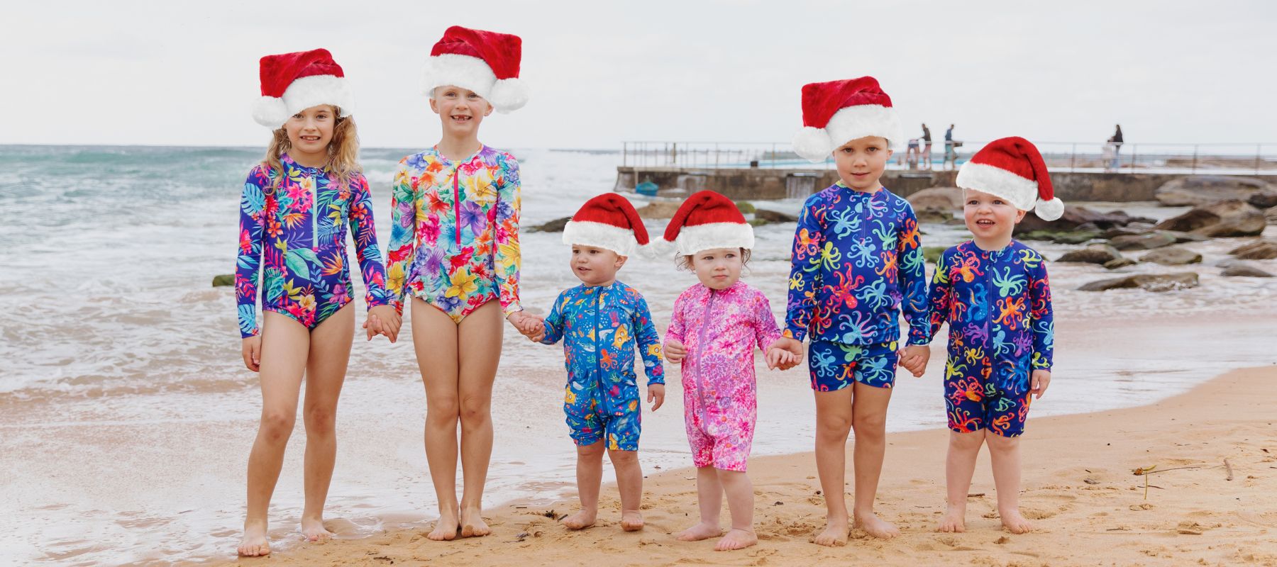 Kids on beach wearing santa hats in Ocean Tales swimwear