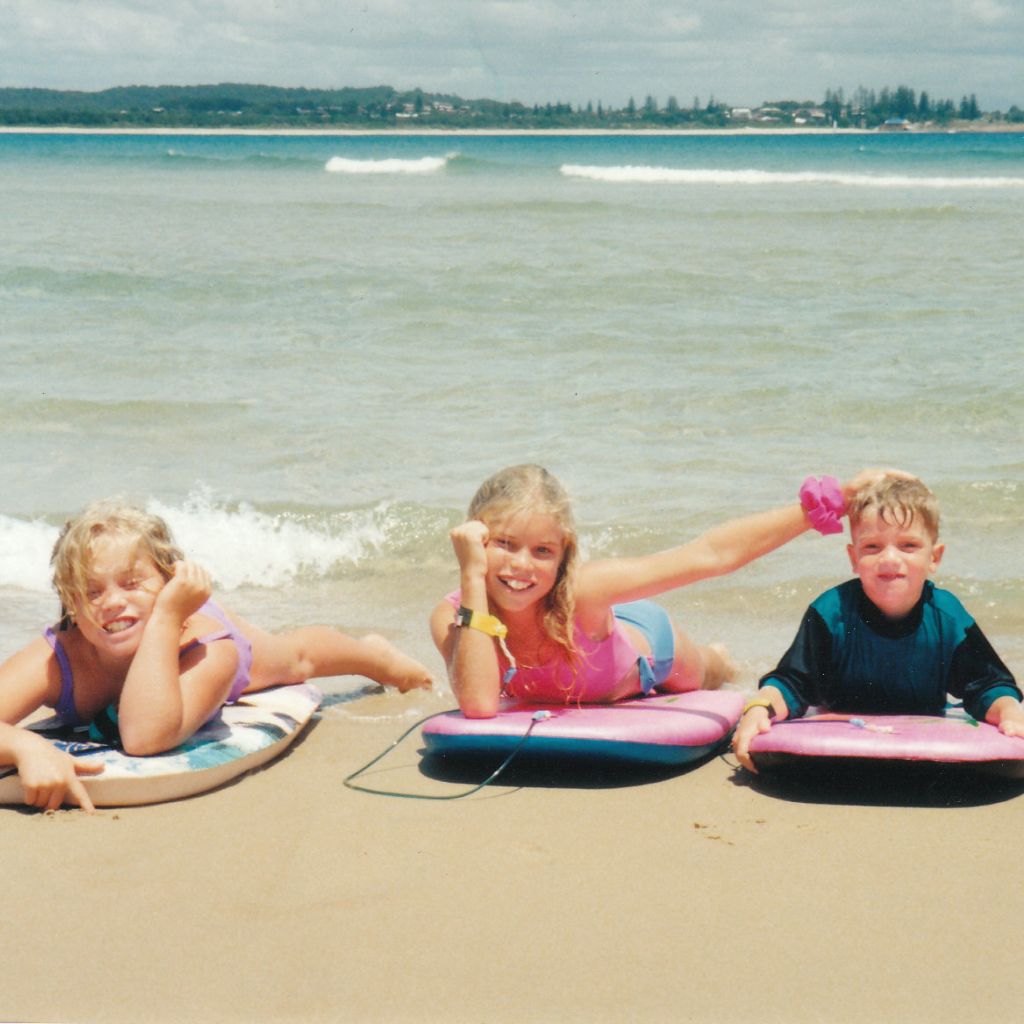 siblings at the beach on their boogie boards
