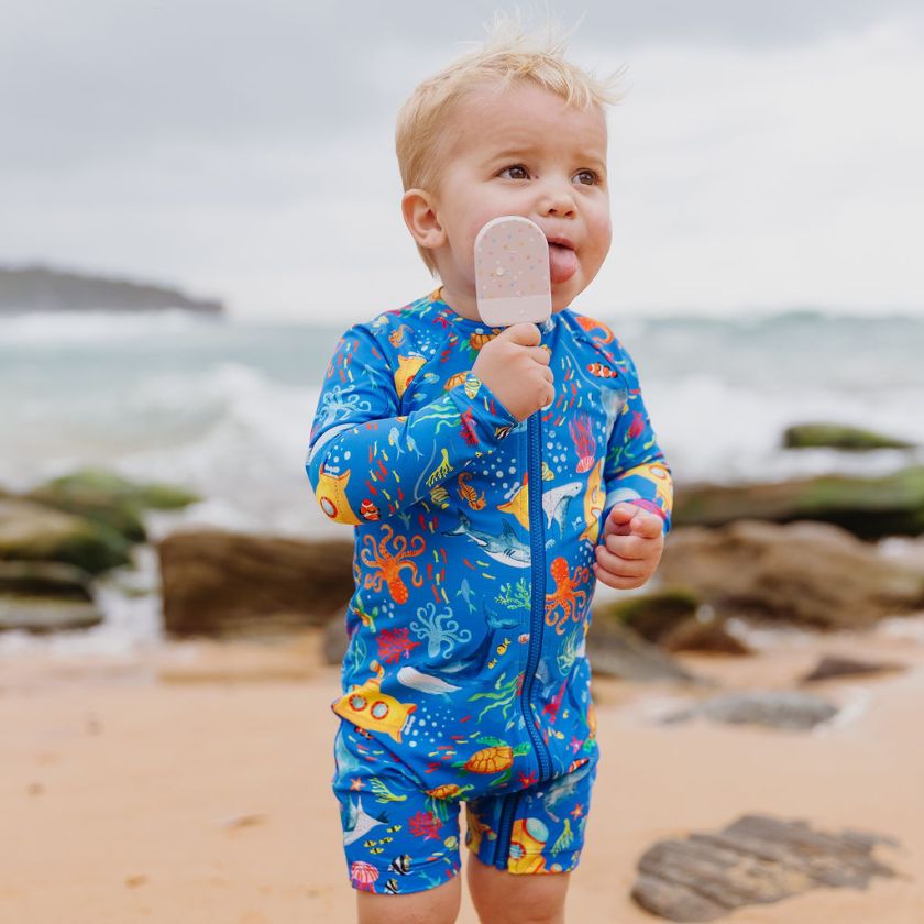 boy on beach licking ice cream wearing ocean tales swimwear
