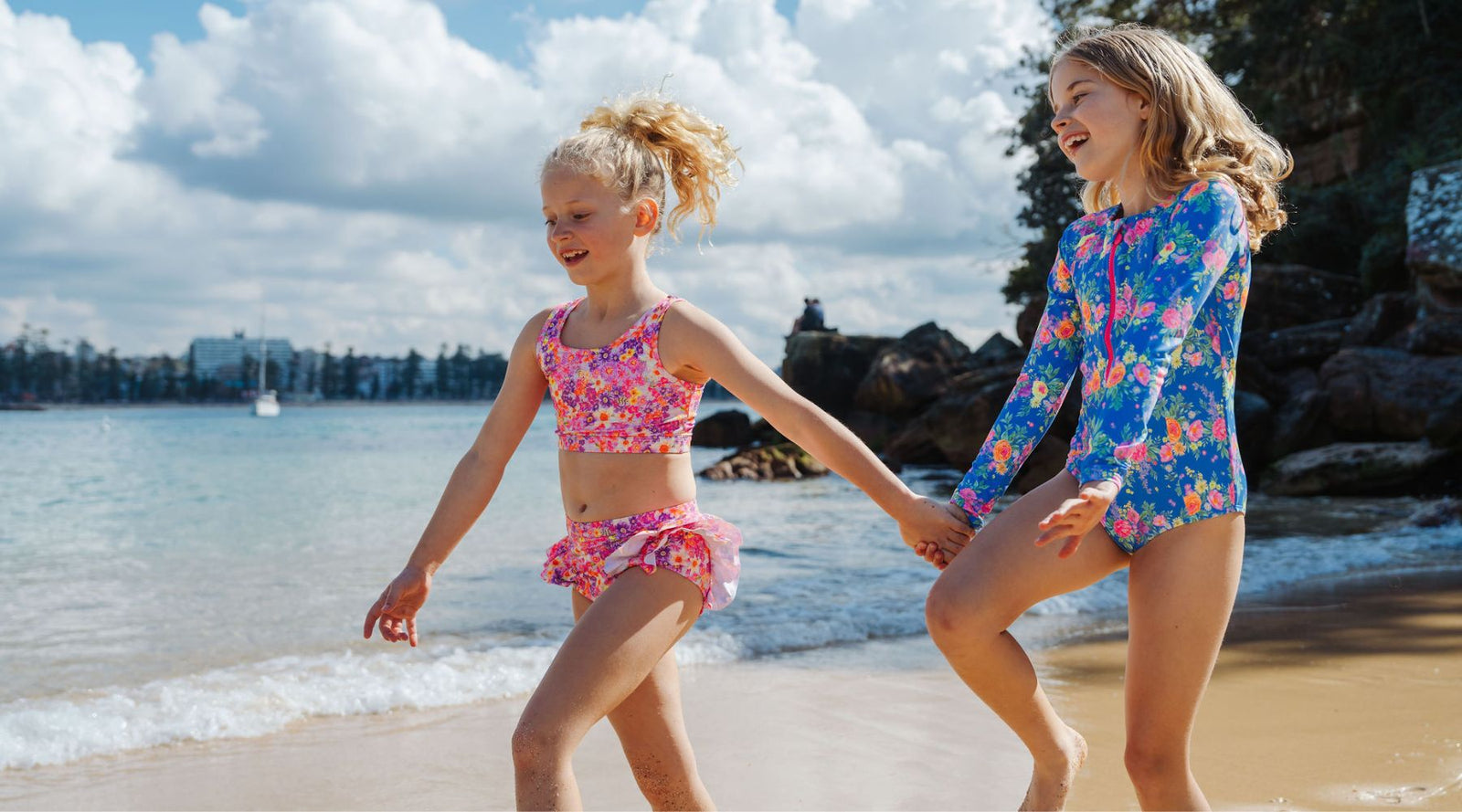 girls skipping along beaching wearing ocean tales cossies