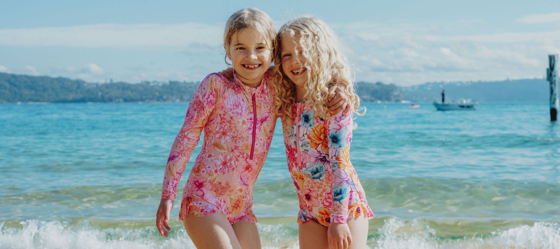 Girls hugging on beach wearing Ocean Tales swimwear